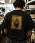 LIVES FOREVER — Cooked 001. Byzantine icon artwork of Shaun Mannagh in Geelong hoops with Jason Akermanis as haloed saint behind him, arms outstretched in celebration, gold leaf background with ornate border, printed on the back of a black heavyweight cotton t-shirt.